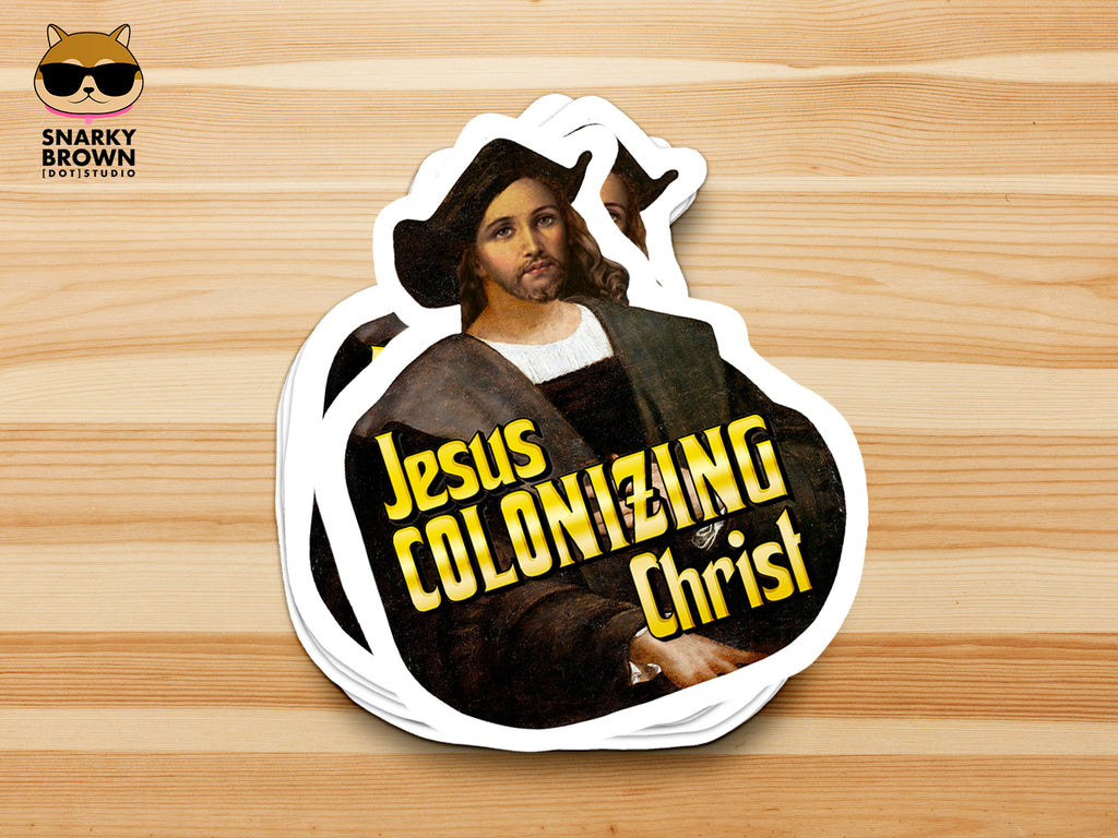 A stack of die-cut stickers featuring a parody art print of Jesus Christ dressed as Christopher Columbus, with the bold yellow text 'Jesus Colonizing Christ'. The stickers are displayed on a light wood grain background, with a 'Snarky Brown Studio' logo in the top-left corner.