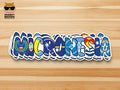 A die-cut sticker spelling 'MICRONESIA' in stylized letters filled with various blue and multicolor Pacific island flag designs, shown on a light wood background. The Snarky Brown Studio logo is visible in the top-left corner.